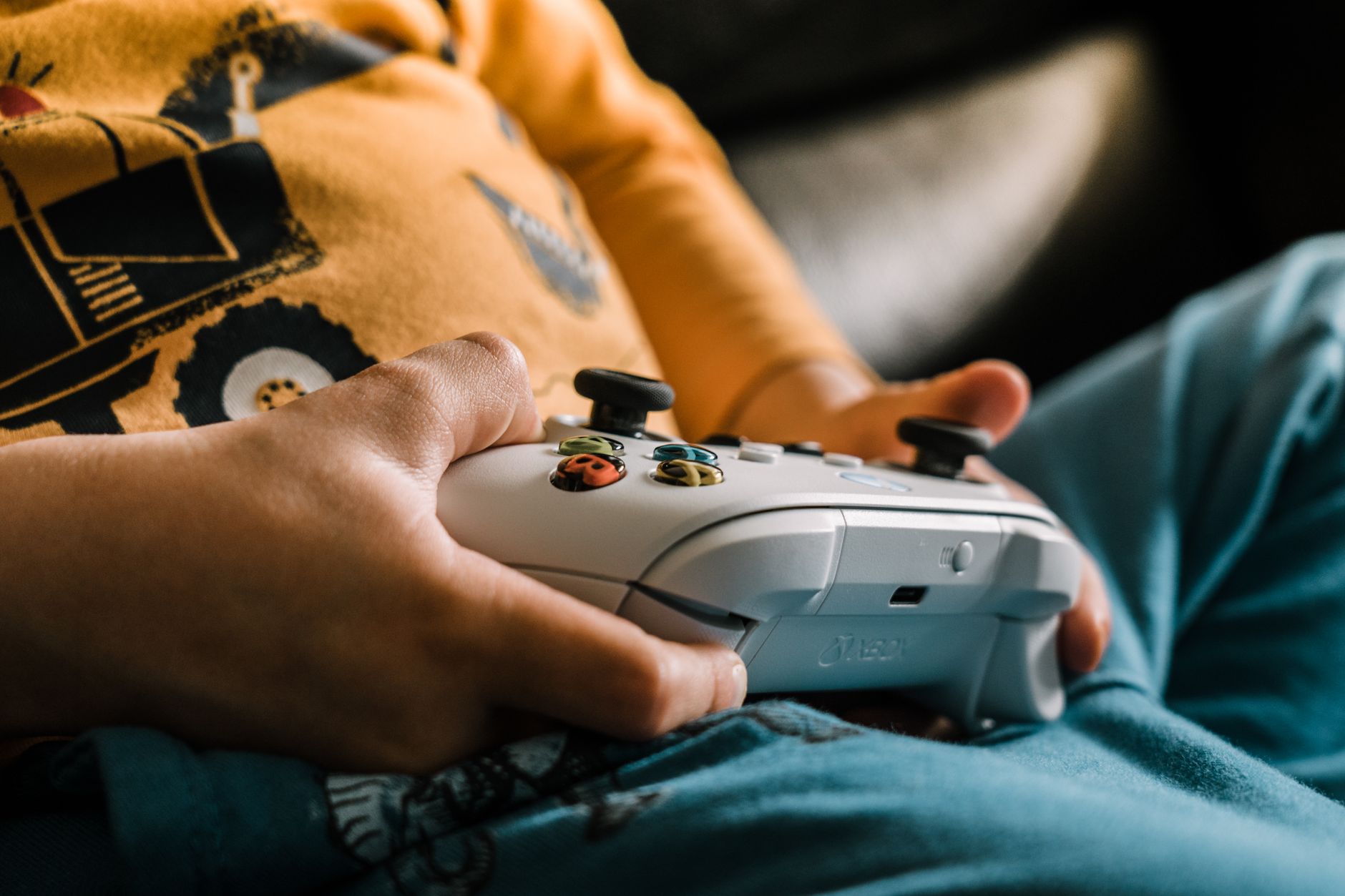 Close-up of a child holding a game controller, focused on video gaming indoors.