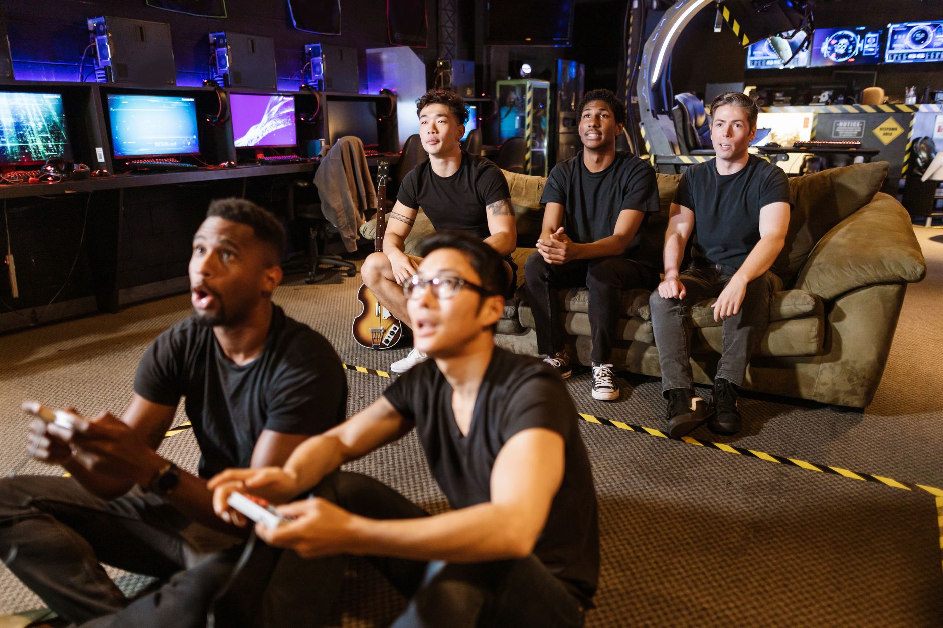 Group of diverse friends enthusiastically playing video games at a modern arcade.