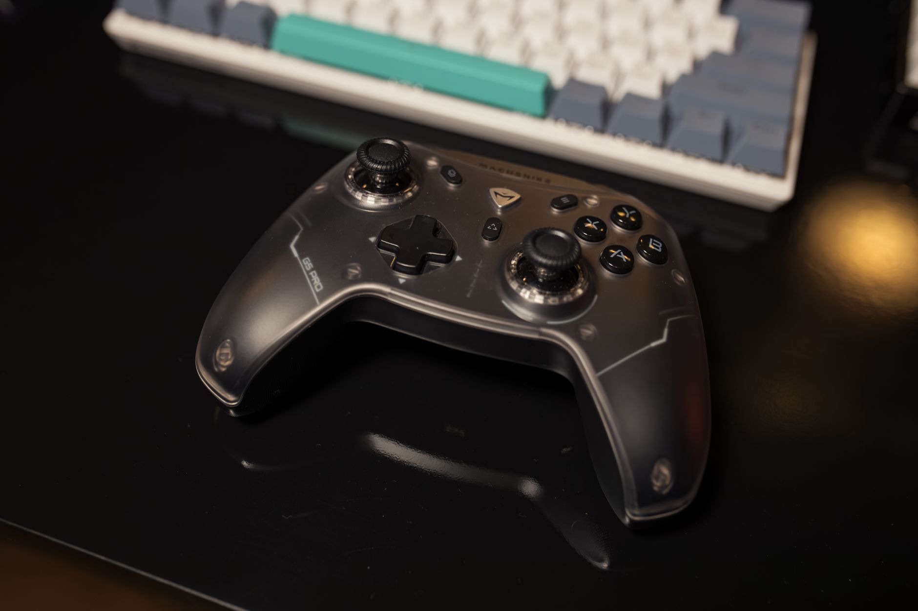 Game controller resting on a desk next to a keyboard, showcasing sleek design in a gaming setup.